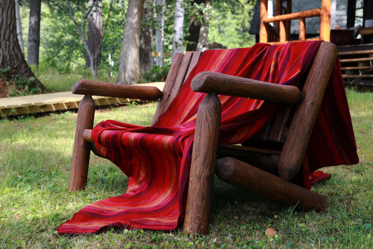 An alpaca blanket draped over an Adirondack style bench